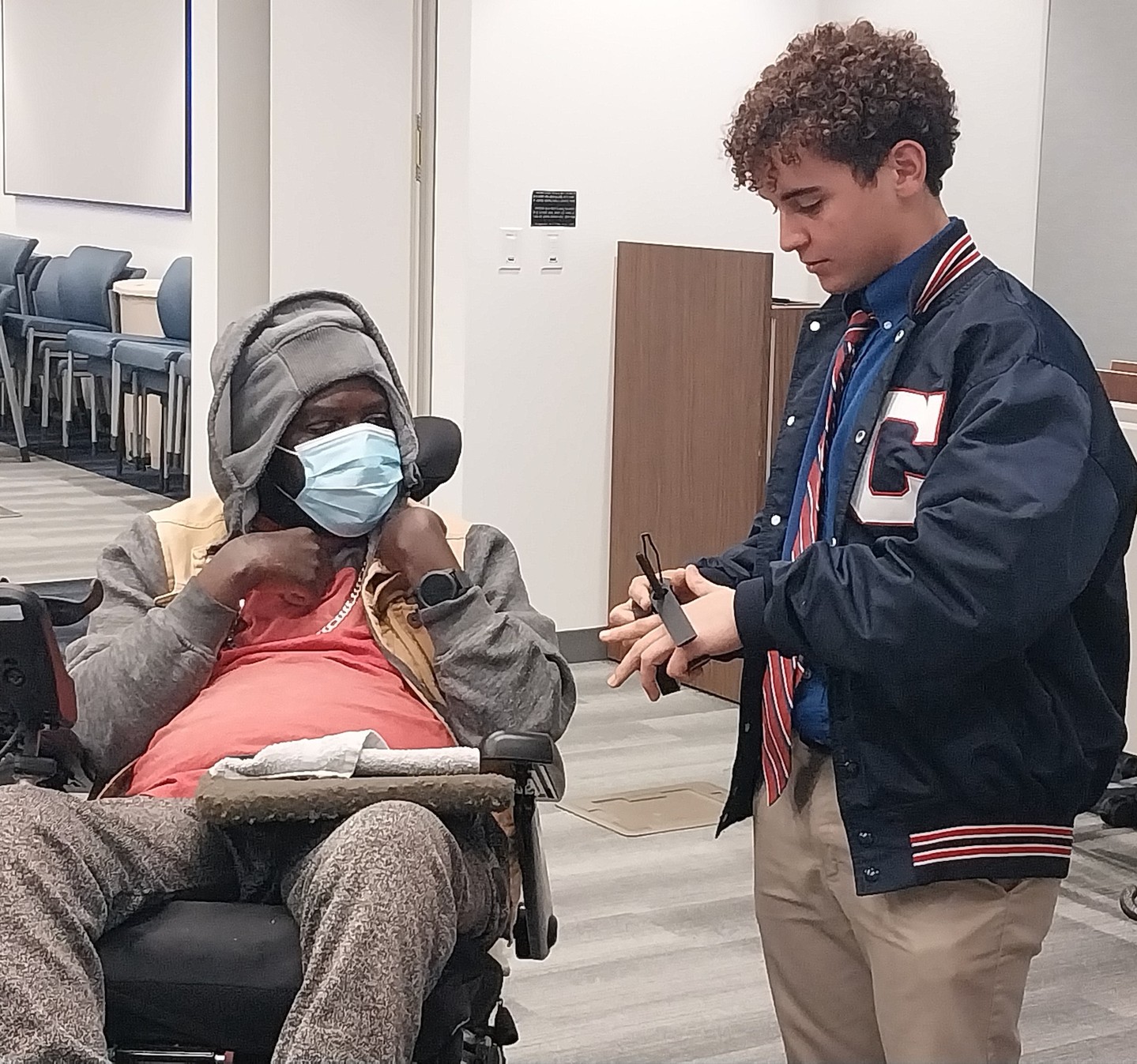 A student demonstrating a 3D-printed assistive device to a patient at the rehabilitation center